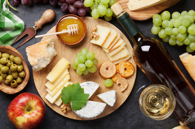 White wine, grape, cheese plate and honey over stone table. Top view